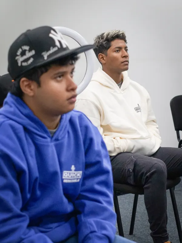 Dos personas con sudaderas de Quick Venezuela, sentadas en una sala