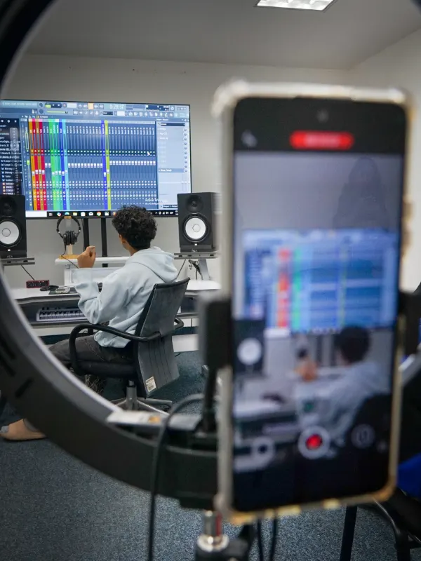 Celular grabando una sesión a través de un aro de luz, con FL Studio en la pantalla del fondo